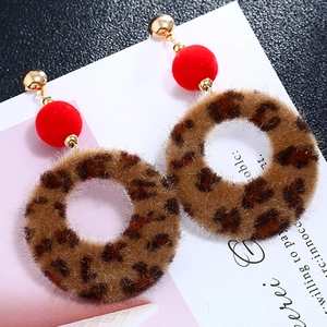 Detail view of leopard print plush hoop earrings with red pom-pom and gold stud
