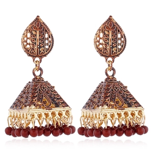 Detail of vintage bohemian Jhumka earrings with ornate bell pendants and red bead drops