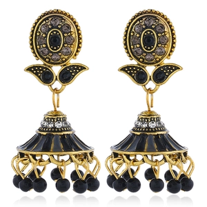 Detail view of retro gold and black enamel flower drop earrings with rhinestones