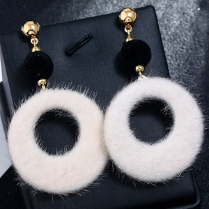 Detail of plush geometric hoop earrings with black suede ball on jewelry box