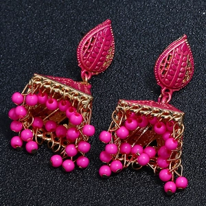 Macro detail of ethnic rose pink Jhumka earrings with ornate beads and floral metalwork