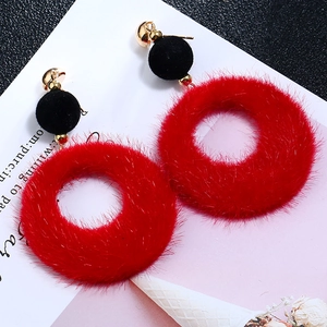 Macro shot of red plush ball and black velvet earrings with golden metal studs