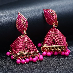 Macro shot of ethnic boho bell earrings with vibrant pink enamel and golden beads