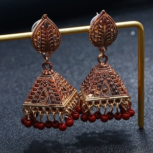 Detailed close-up of retro bell drop earrings with red beads and bronze hollow patterns