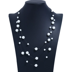Close-up of triple-layered faux pearl necklace with multi-size beads on black wire