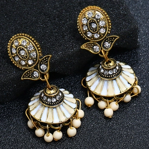 Macro view of bohemian jhumka earrings with gold finish and white bead tassels