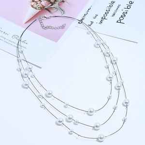 Detailed view of triple-layered faux pearl necklace with silver lobster clasp and steel wire