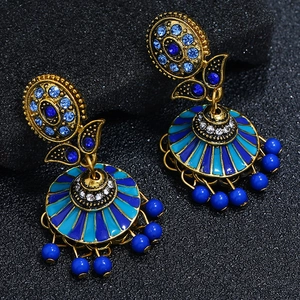 Detail of vintage bohemian Jhumka earrings with blue enamel sunburst and hanging beads