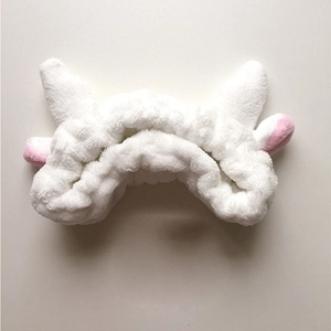 Détail du bandeau en peluche blanche douce avec oreilles roses et tissu élastique