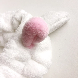 Gros plan sur le bandeau en peluche blanche avec des détails de pompons roses