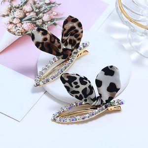 Détail de barrettes à nœuds léopard avec strass et oreilles en tissu sur base en pierre