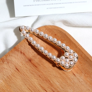 Détail d'une barrette à cheveux dorée ornée de perles avec un design triangulaire
