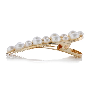 Détail de perles blanches linéaires sur une pince à cheveux en métal doré de type croco