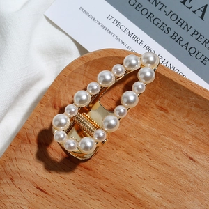 Vue détaillée d'une barrette en perles dorées sur un plateau en bois minimaliste