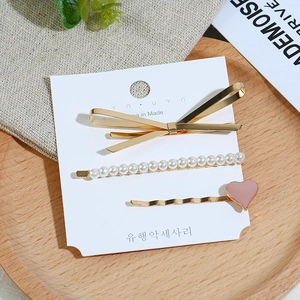 Lot de trois pinces à cheveux dorées avec perles et cœur rose sur carte blanche
