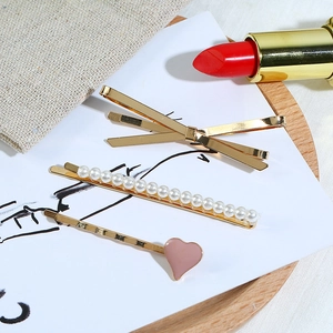 Lot de trois barrettes avec nœud doré, perles et cœur rose sur un plateau chic