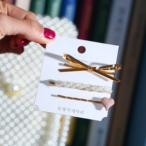 Détail de trois barrettes à cheveux avec perles, nœuds dorés et petit cœur en émail rose