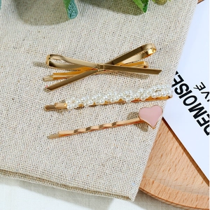Ensemble de 3 barrettes à cheveux avec nœud doré, perles et cœur rose sur fond rustique