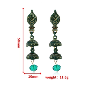 Dettaglio macro di orecchini vintage Jhumka con perline verdi e incisioni etniche