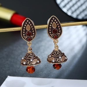 Detail macro-opname van boho-oorbellen met rode kristallen en een gouden afwerking