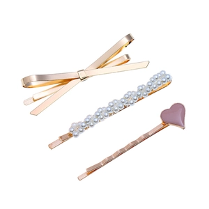 Set de trois barrettes avec nœud doré, perles et pendentif cœur violet sur fond blanc