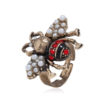 Dettaglio dell'anello ape in bronzo vintage con perle bianche e cristalli rossi