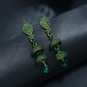 Gros plan de boucles d'oreilles Jhumka vintage vert émeraude aux motifs dorés ciselés