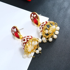 Detail van boheemse Jhumka-oorbellen met rode edelstenen, wit emaille en parels