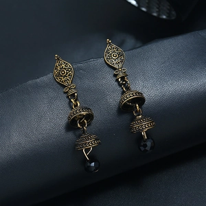 Dettaglio degli orecchini Jhumka dorati con motivi decorativi e perle di cristallo nero