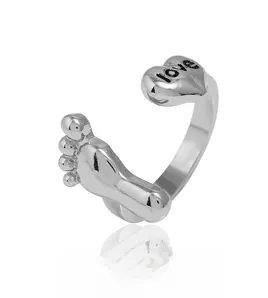 Détail d'une bague ouverte argentée avec cœur 3D et motif de petite empreinte de pied