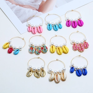 Flat lay of vintage shell hoop earrings with pearls in multiple vibrant summer colors