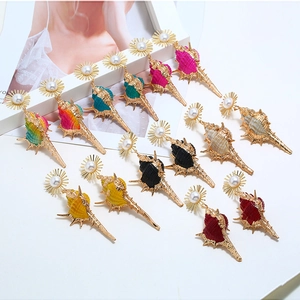 Macro detail of bohemian seashell earrings with pearl sun studs and colorful finishes