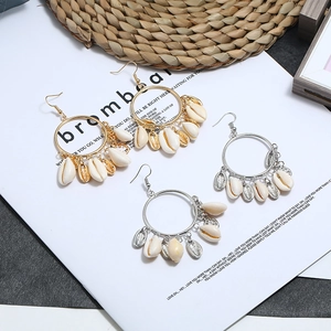 Close-up of bohemian hoop earrings with natural shells in gold and silver finish