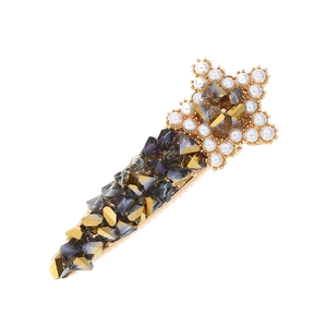 Detailed macro view of a gold star hair clip with pearls and sparkling crystals