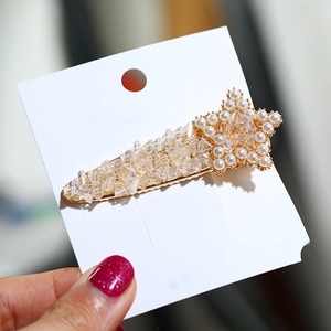Elegant gold star hair clip with pearls and sparkling crystals on display card