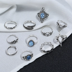 Gros plan sur un lot de 10 bagues vintage argentées avec pierres bleues et plumes bohèmes