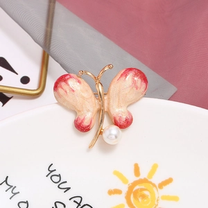 Eleganter Schmetterlings-Brosche in Gold mit cremigen Flügeln und roten Glitzer-Akzenten