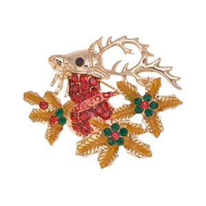 Detail shot of golden Christmas reindeer brooch with red rhinestones and holly berry design