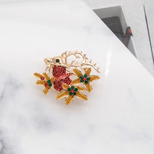 Detail of golden reindeer brooch with sparkling red rhinestones and holly leaves