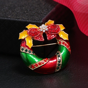 Broche couronne de Noël en émail avec strass colorés et nœud sur fond en soie rouge