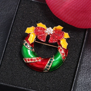 Broche couronne de Noël avec nœud rouge et strass colorés sur velours noir