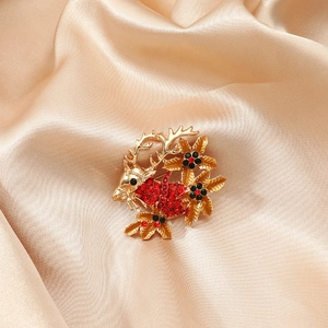 Golden Christmas reindeer brooch with red rhinestones on champagne silk fabric background