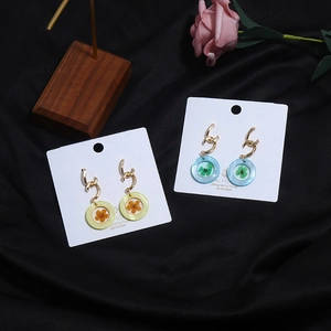 Detalle de pendientes geométricos de acrílico con flores secas reales y plata S925