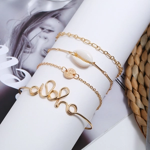 Detail von vierteiligem goldenem Boho-Armbandset mit Muschel, Münze und Aloha-Armreif