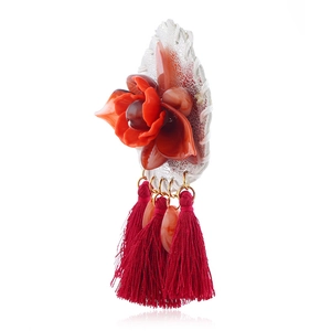 Detail of red acrylic flower brooch with vibrant silk tassels and marble texture beads