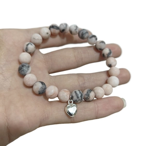 Pink zebra stone bead bracelet with silver heart charm on wrist for couples