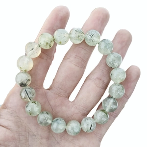 Natural green prehnite beaded bracelet with needle inclusions held in hand on white background
