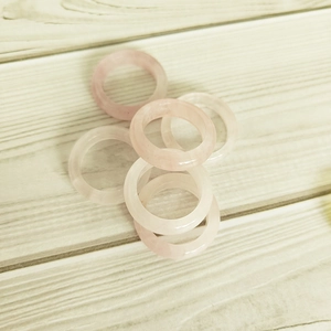 Group of 6mm polished natural pink agate rings displayed on a white wood surface