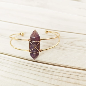 Detail of handmade gold wire-wrapped bracelet with a natural purple hexagonal crystal