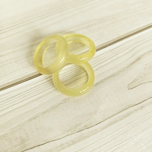 Three translucent yellow agate gemstone rings stacked on a natural wooden background